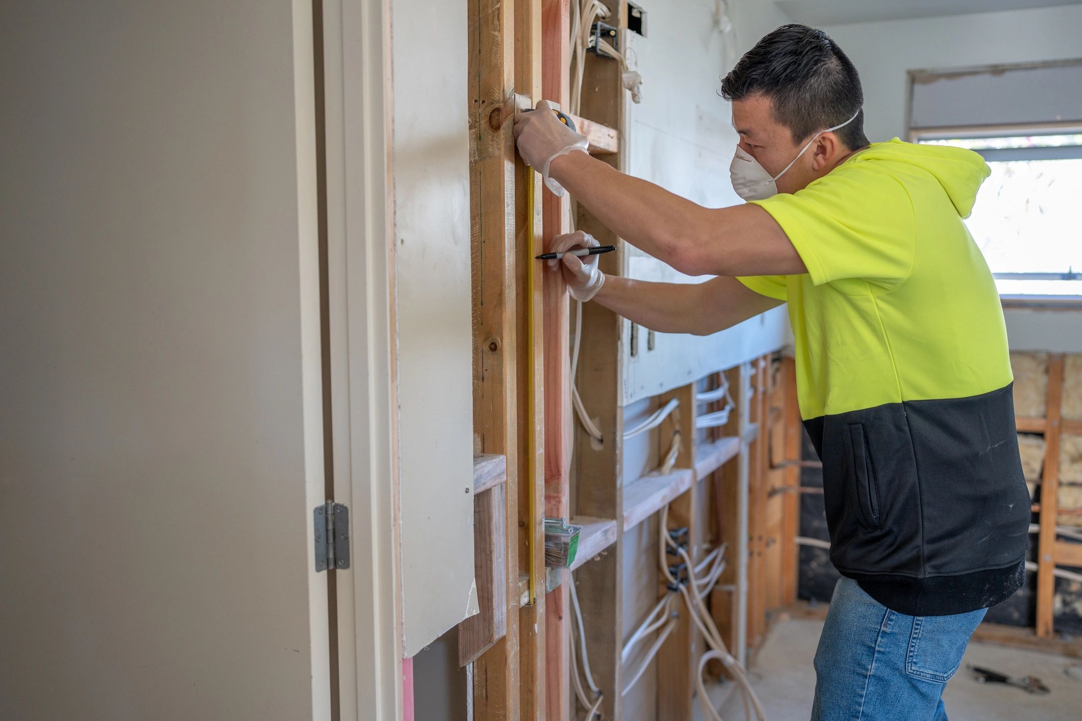 Contractor measuring interior wall framing during renovation